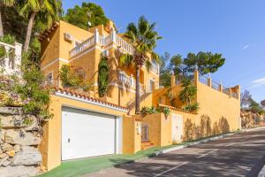 a yellow house with a garage door on a street at Macondo Altea Hills in Altea