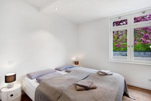 a white bedroom with a bed and two windows at Gut Vasbach Ferienwohnungen in Kirchhundem