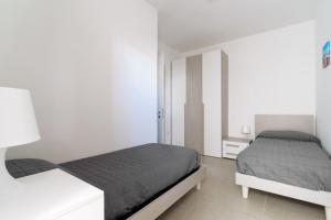 a white bedroom with two beds and a white cabinet at Casa d'a mare in Torre San Giovanni Ugento