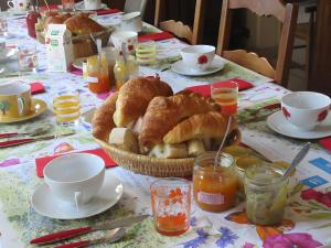 a table topped with a basket of croissants and coffee at Chambres Paysannes Lecarpentier - in Fontenay
