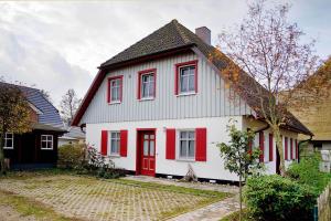 a white and red house with a red door at Haus Schilfblick in Wieck