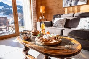 a living room with a table with food and a couch at Tié No Appartement Chaleureux in Manigod