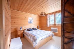 a bedroom with a bed in a wooden cabin at Tié No Appartement Chaleureux in Manigod