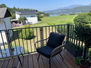 a chair sitting on a deck with a view of a field at Casa Tapeo in Schiefling am See