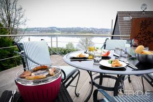 a table with food on a balcony with a view of the water at Seekoje - Haus Am Möhnesee in Möhnesee