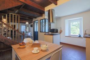 a kitchen with a wooden table and a dining room at Maison de vacances Kerkohann in Tressignaux