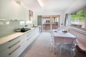 a kitchen with white cabinets and a table and chairs at Apart Wellness Alpino con minispa in Soraga
