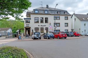 a large white building with cars parked in front of it at Gästezimmer St Wendel in Prüm