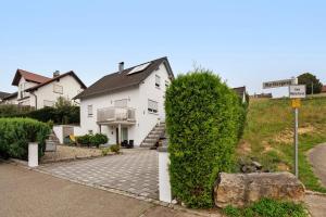 a white house with a large bush in front of it at Ferienwohnung am Wartberg in Herbrechtingen