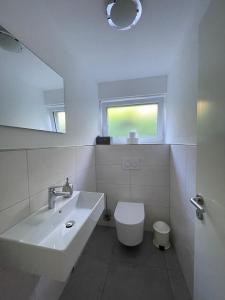 a white bathroom with a sink and a toilet at Ferienwohnung Nell in Daisendorf +10 photos
