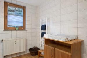 a white tiled bathroom with a sink and a window at Ruhige Schwarzwald Ferienwohnung in Buchenbach +24 photos