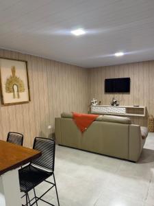 a living room with a couch and a television at Mini Casa Privativa -Praia do Tombo in Guarujá