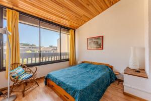 a bedroom with a bed and a window and a chair at La Forestière Cap Ferret - Réf 2 in Lège-Cap-Ferret