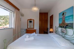 a bedroom with a white bed with a large window at Captain Spiros Paxoi in Gaios