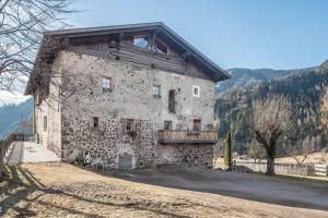 a stone building with a balcony on the side of it at Moserhof Ferienwohnung Sunnseit in Sarntal