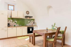 a kitchen with white cabinets and a wooden table and chairs at Moserhof Ferienwohnung Sunnseit in Sarntal