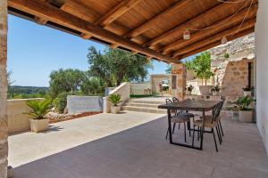 an outdoor patio with a wooden pergola and a table and chairs at Trulli House in Putignano