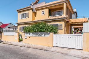 a yellow house with a white fence at Casa do Rei - Charneca in Charneca