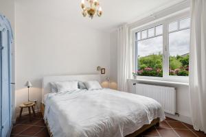a white bedroom with a bed and a window at Ferienhaus Karinella in Scharbeutz