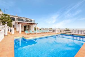 a swimming pool with chairs and a house at Ericito in Denia