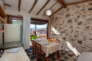 a dining room with a table and a stone wall at Hora Vona in Orosei