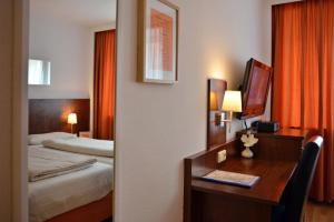 um quarto de hotel com uma secretária e uma cama em Hotel Italia em Munique