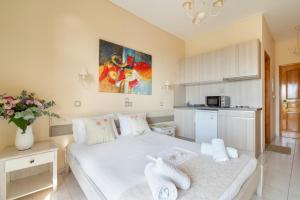 a bedroom with a white bed and a kitchen at Nontas Home 23 in Kalamitsi
