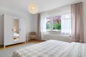 a white bedroom with a bed and a window at Ferienwohnung Am Buchbühl in Stockach