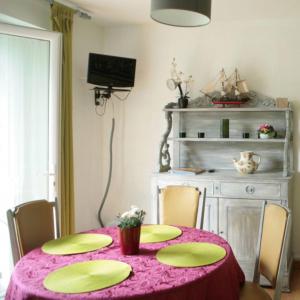 a dining room with a pink table with chairs and a television at L'avocette in Sarzeau +2 photos