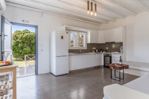 a white kitchen with a refrigerator and a table at Ow Andros Suite 1,Private Whirlpool in Andros