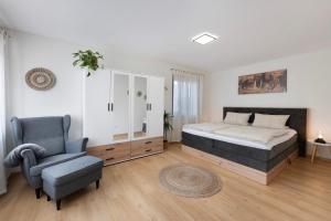 a bedroom with a king sized bed and a chair at Baumschule Rombach - 'Spatzennest' in Herbolzheim