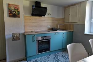 a kitchen with blue cabinets and a sink and a stove at Chez Jeanne, charmante maison in Dossenheim-sur-Zinsel