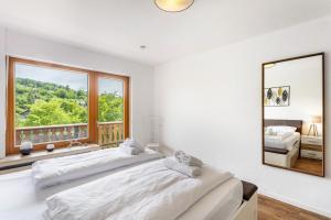 two beds in a bedroom with a mirror and a window at Haus Sonnenblick in Diemelsee