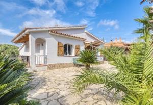 a white house with palm trees in front of it at Costacabana - Villa Nicky in Lloret de Mar