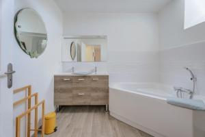 a white bathroom with a tub and a mirror at La ferme d'Alcide in Québriac +20 photos