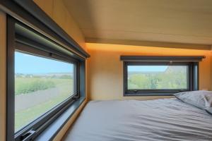 a bedroom with a bed and a large window at Tiny House 'bada' Vue Mer in Langueux