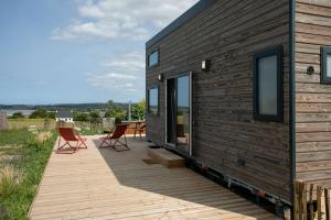 a house with two chairs on a wooden deck at Tiny House 'bada' Vue Mer in Langueux