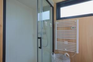 a bathroom with a shower and a glass door at Tiny House 'bada' Vue Mer in Langueux +19 photos