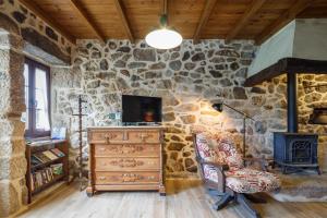 a stone walled living room with a tv and a chair at C Vilamide in Parada de Achas