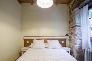 a bedroom with a bed and a stone wall at C Vilamide in Parada de Achas