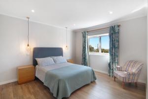 a bedroom with a bed and a chair and a window at Casa no Campo com vista mar in Loulé +17 photos