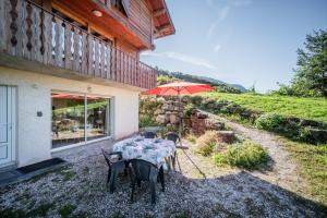 a table with a red umbrella sitting outside of a house at Chalet Les Mios, chez Isa in Vacheresse