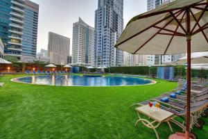 een zwembad met stoelen en een parasol in een stad bij Marina View Deluxe Hotel Apartment in Dubai