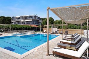 a swimming pool with lounge chairs next to a building at Iguana studio 8 in Preveza +12 photos