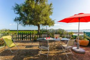 a table and chairs with a red umbrella and the ocean at Maison de la côte in La Flotte