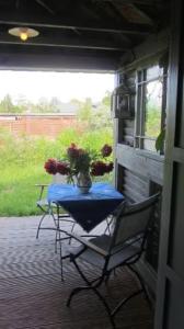 a table and chairs on a porch with a vase of flowers at Charlottes Landlust in Ribnitz-Damgarten
