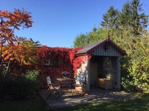 a small cottage with a table and red ivy at Charlottes Landlust in Ribnitz-Damgarten