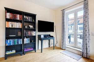a room with a desk and a tv and book shelves at Ferienwohnung Flür in Weiler-Simmerberg