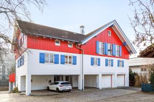 a red and white house with a car parked in front at Ferienwohnung Flür in Weiler-Simmerberg