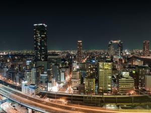 a night view of a city with buildings at Hotel Hanshin Osaka in Osaka